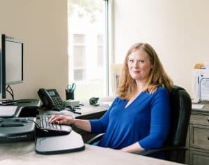 Woman sitting at a computer desk, looking at the camera